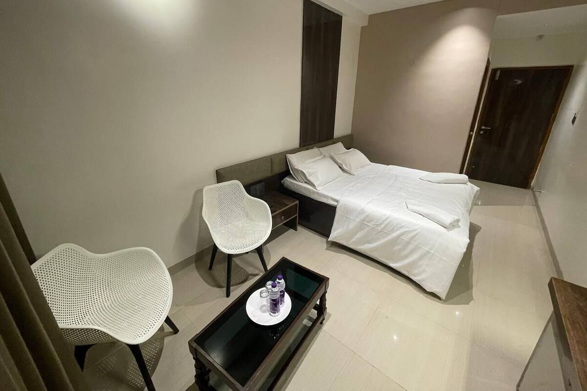 Une chambre d’hôtel avec un lit, une petite table avec un plateau, deux chaises et une porte.