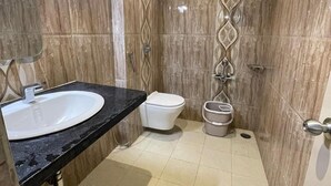Un baño con pared de mármol, un lavabo, un inodoro y zona de ducha.