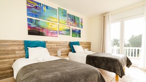 Habitación de hotel con dos camas, cabecero de madera, balcón y arte abstracto de colores en la pared.