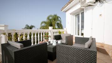 An outdoor seating area with wicker furniture and a white railing.