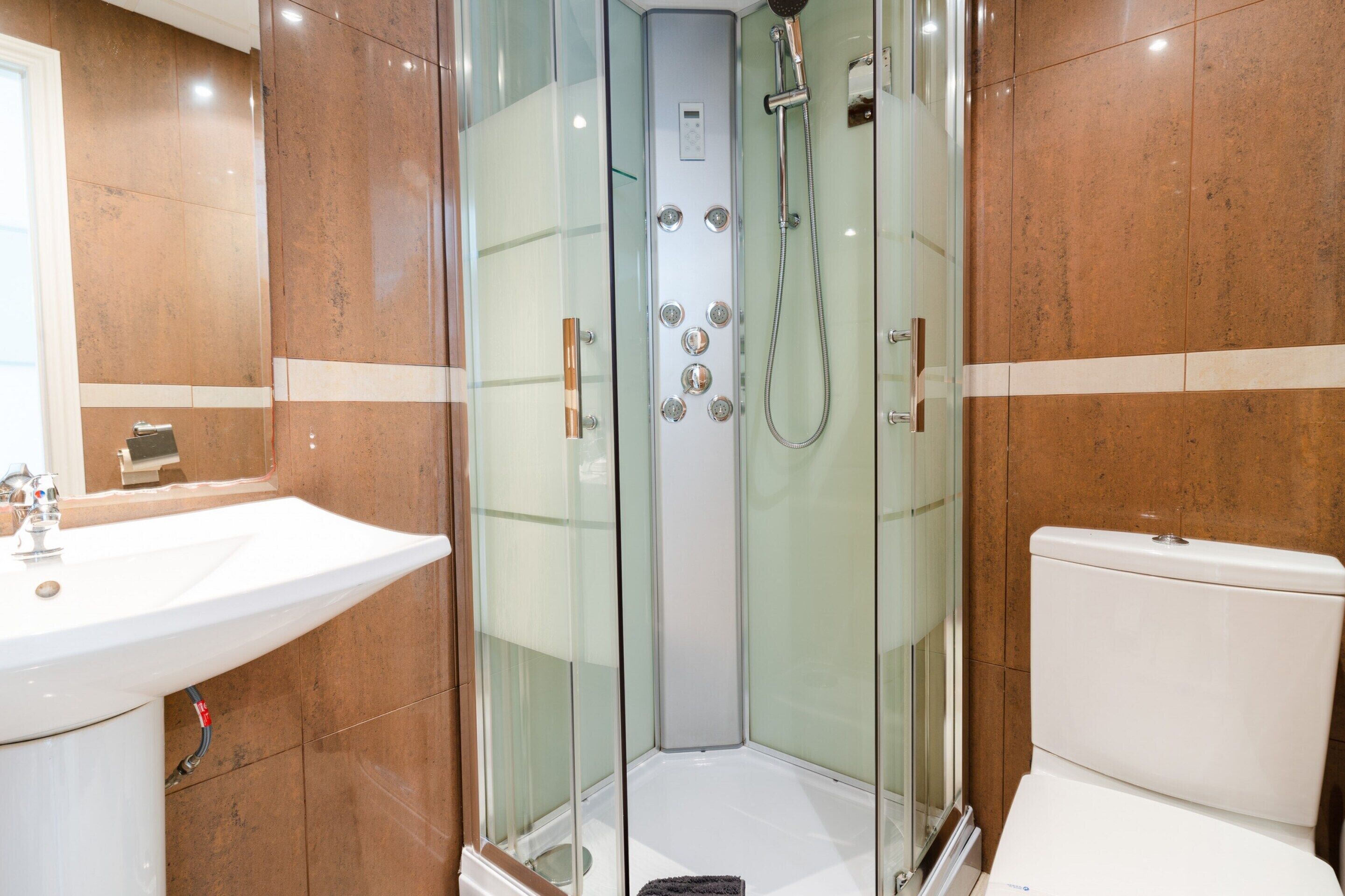 Ein modernes Badezimmer mit einer gläsernen Duschkabine, einem weißen Waschbecken und einer Toilette.