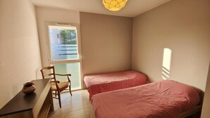 A small, well-lit room with two single beds, a desk with a chair, and a window providing natural light. - SAINT-AYGULF Sea view, 4 pers air conditioning, swimming pool, near Calanques corailleurs  (Fréjus)