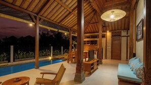 Ein Poolbereich mit Holzpergola, Sitzgelegenheiten und einem Fernseher.