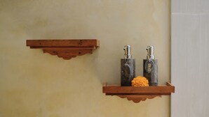 Ein Badezimmer mit Holzböden, auf denen sich zwei Metallbehälter und eine Blume befinden.