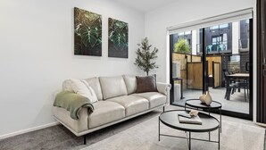 Un salon moderne avec un canapé en cuir, une table basse ronde et deux œuvres d’art accrochées au mur.