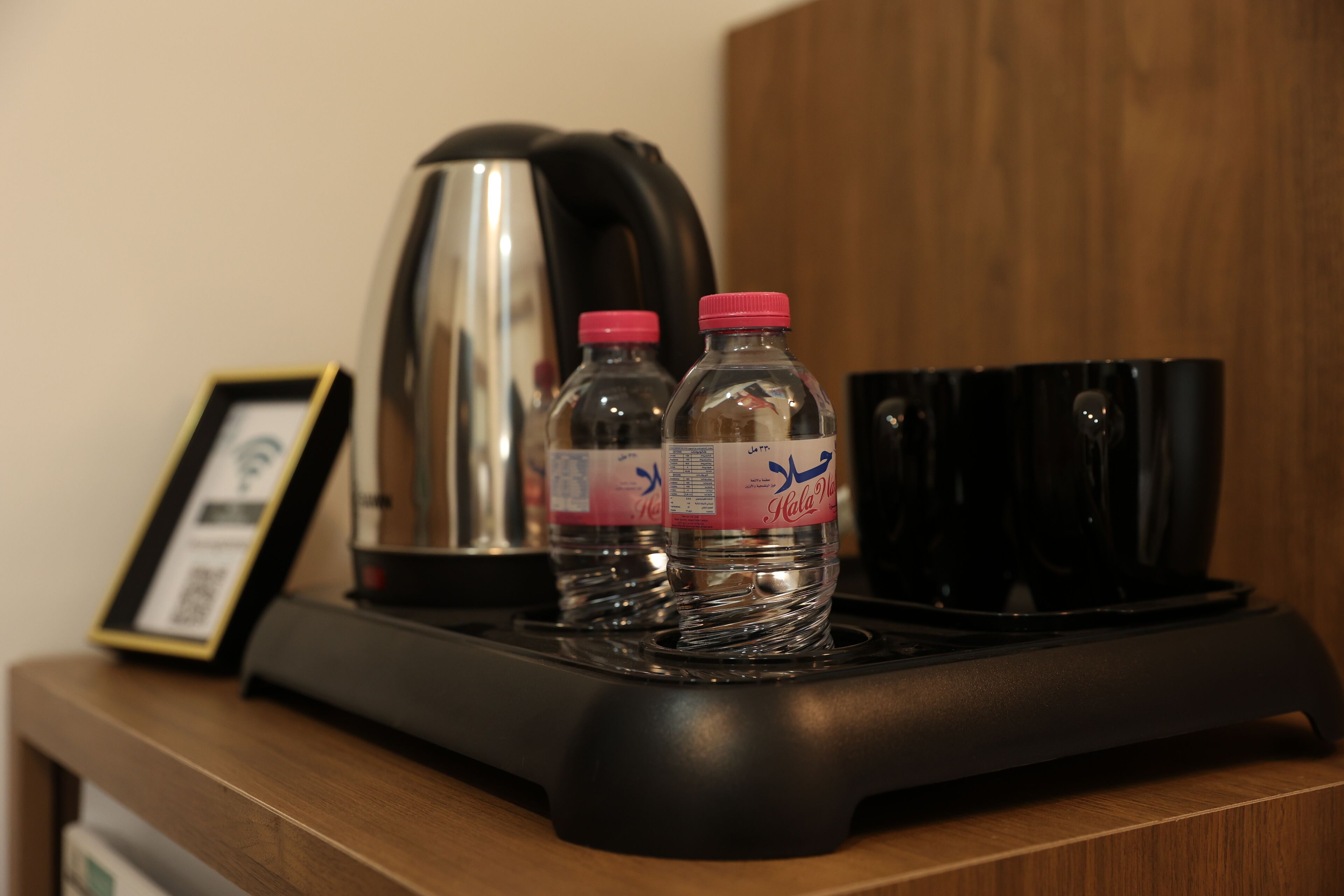 Un coin cuisine comprenant une machine à café, deux bouteilles d’eau et un certificat encadré, le tout posé sur un comptoir en bois.