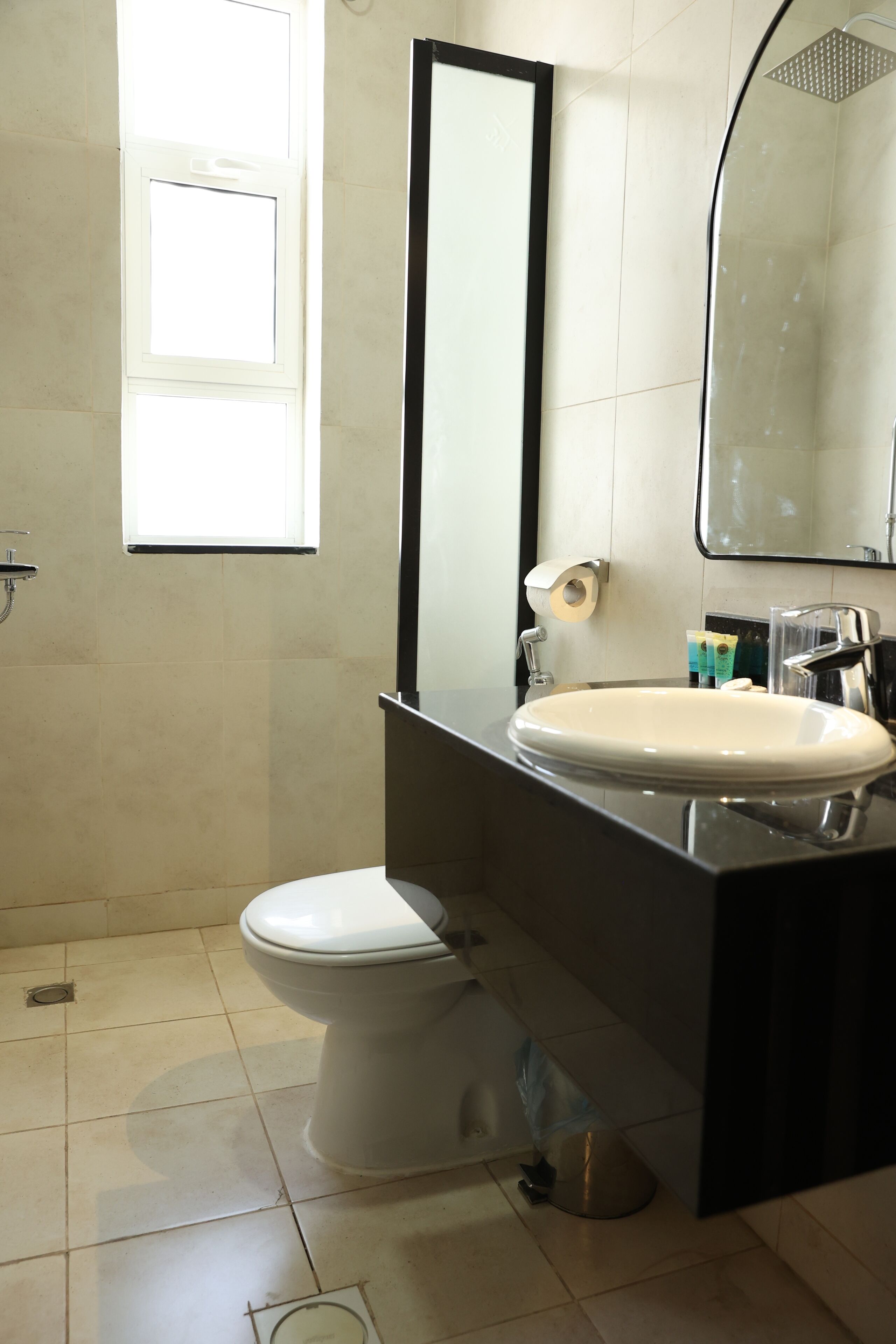 A bathroom with a toilet, sink, mirror, and shower.