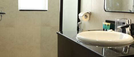 A bathroom with a toilet, sink, mirror, and shower.