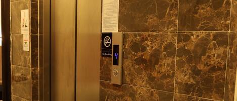 An elevator with a digital display indicating floor 4, surrounded by marble walls.