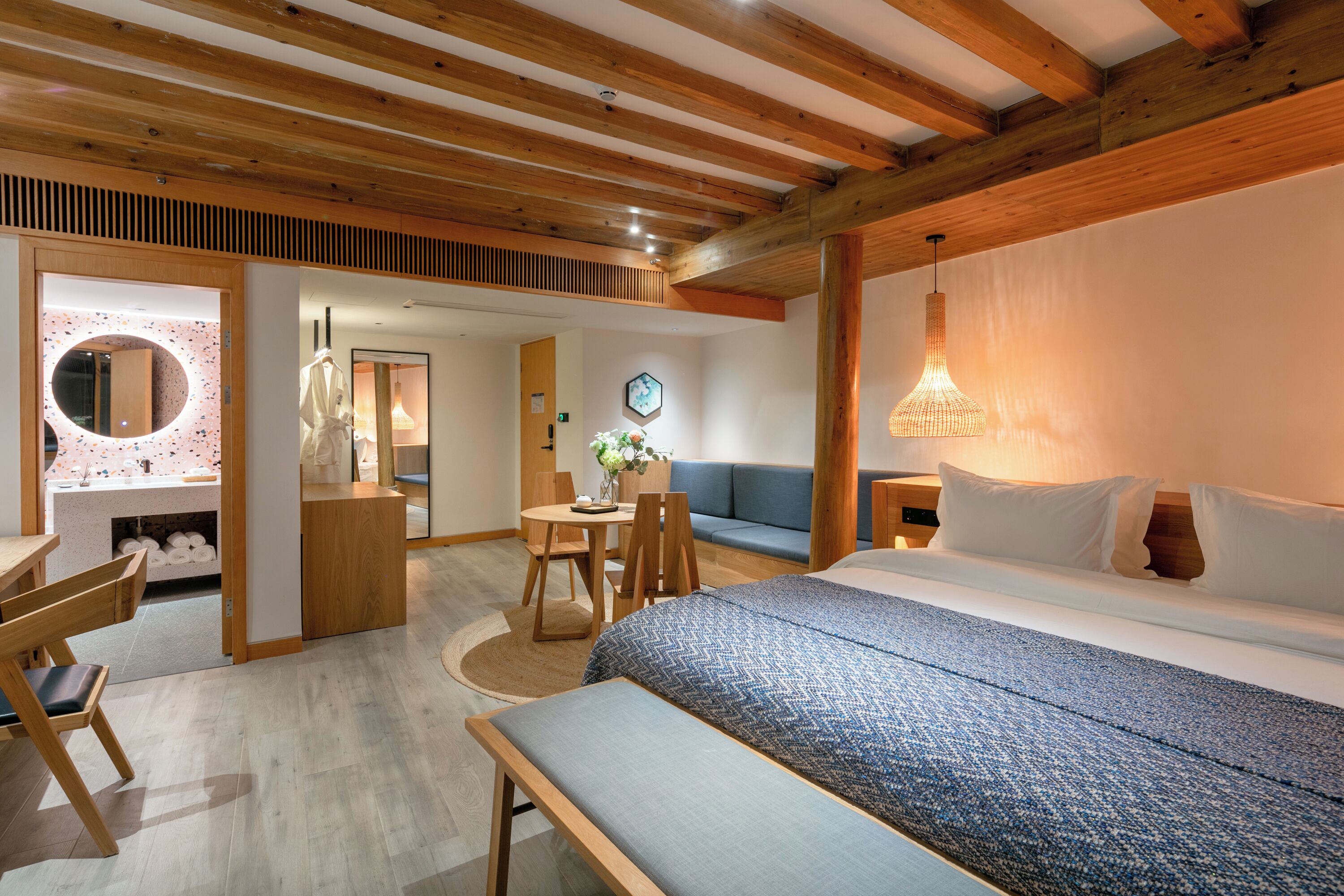 A bedroom with a bed, bedside table, and a wooden ceiling.