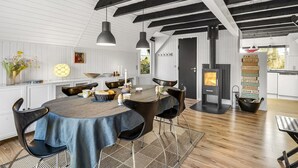 A modern kitchen with a central island, pendant lighting, and a black stove. - "Sampo" - 150m to the fjord by Interhome (Tarm)