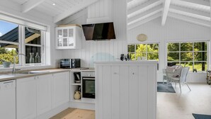 A modern kitchen with white cabinetry, a built-in microwave, and a large window offering a view of greenery.