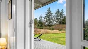 A wooden deck with a view of a grassy yard and trees.