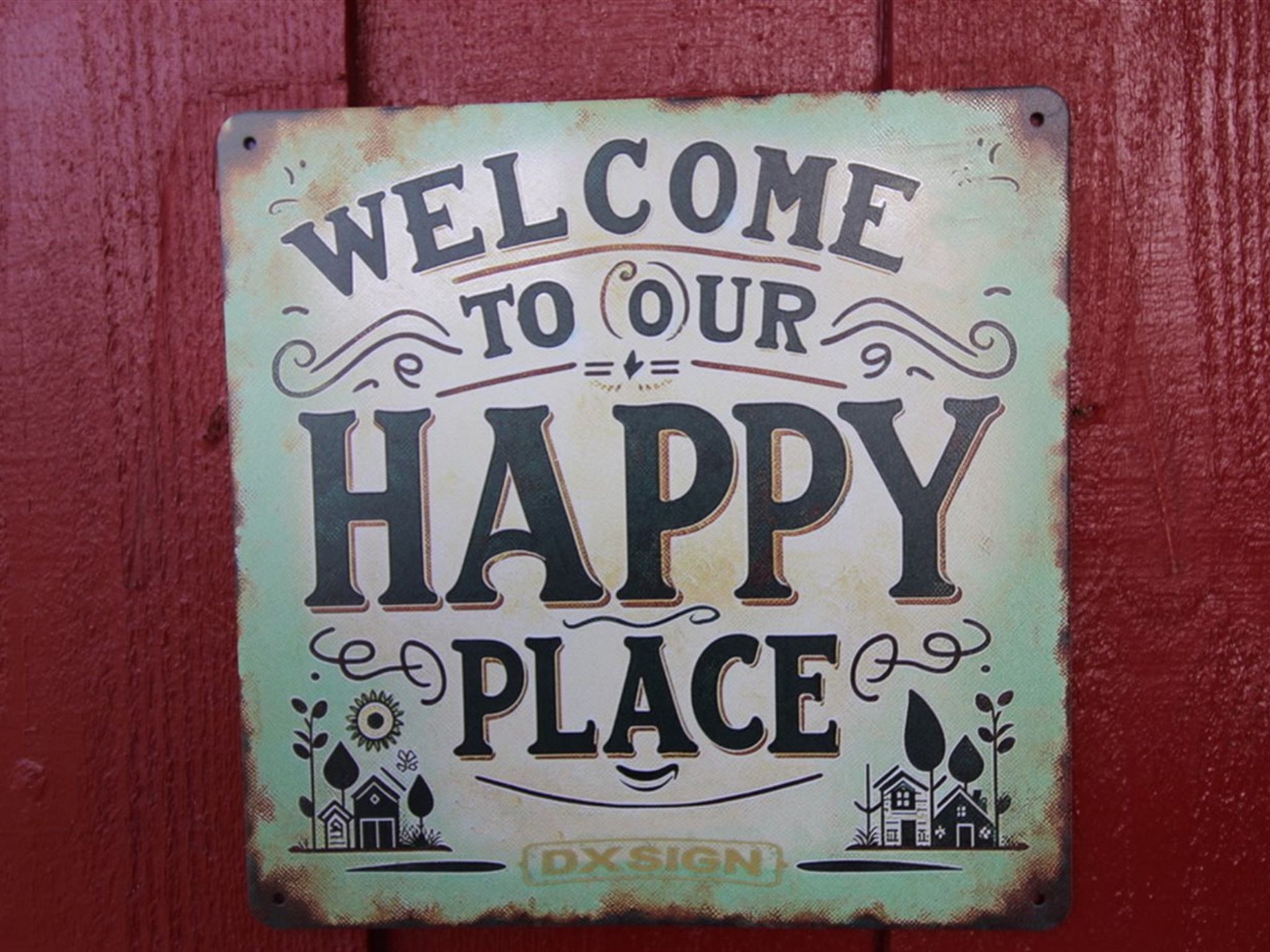 A welcome sign with the text "WELCOME TO OUR HAPPY PLACE" and decorative elements including stylized houses and plants.
