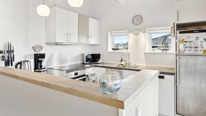 Una cocina moderna con armarios blancos, encimera de madera, cafetera, microondas y refrigerador con imanes.