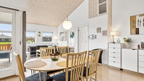 Una cocina moderna con armarios de madera, un comedor con una mesa redonda y sillas, y vistas al exterior.