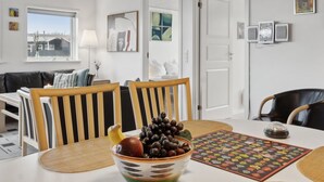 Un comedor con una mesa dispuesta para dos personas, un cuenco de fruta y un camino de mesa colorido.