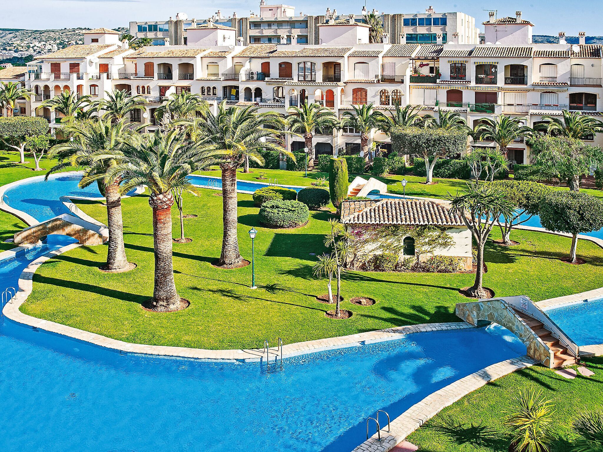 Ein Resort mit Swimmingpool, Palmen und Blick auf die umliegenden Gebäude.