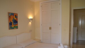 A hotel room with two beds, a painting on the wall, and a wardrobe.