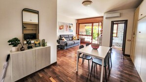 A modern living room with a sofa, TV, and a dining area with a table and chairs.