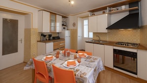 A compact kitchen with a dining area, equipped with a microwave, stove, and sink. - Vacation home Ines by Interhome (San Bernardino)