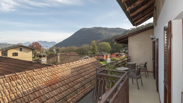 A balcony with a view of a mountain, a wooden ceiling, and a table with chairs. - Vacation home Ines by Interhome (San Bernardino)