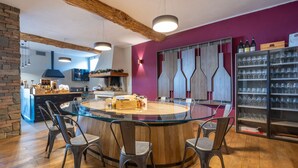 A modern kitchen with a round glass table, wooden chairs, and a wine refrigerator. - Tenuta Bricco San Giorgio by Interhome (Vinchio)