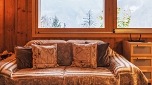 A cozy room with a wooden interior, a bed with patterned bedding, and a view of mountains through two windows. - Chalet Grepon by Interhome (Nendaz)