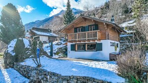 A wooden chalet with a balcony, surrounded by snow-covered mountains and a stone wall. - Chalet Grepon by Interhome (Nendaz)