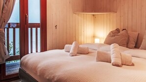 A wooden room with a bed, a window with curtains, and a door. - Chalet Grepon by Interhome (Nendaz)