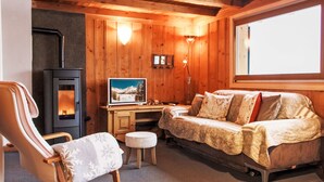 A cozy cabin interior with a wooden interior, a sofa, a chair, a TV, and a fireplace. - Chalet Grepon by Interhome (Nendaz)