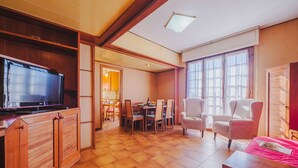 A spacious living area with a television, wooden furniture, a dining table, and large windows. - Menesini by Interhome (Viareggio)
