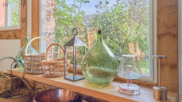 A wooden shelf with wicker baskets, a glass bowl, a lantern, and a glass vase. - 2 Chaumières normande by Interhome (Le perrey)