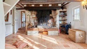 A rustic interior with a stone fireplace, wooden beams, and a tiled floor. - 2 Chaumières normande by Interhome (Le perrey)