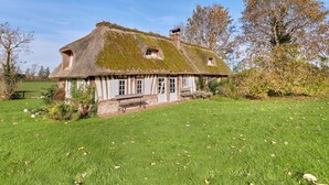 A traditional thatched-roof house with a sloped roof, a small porch, and a well-maintained lawn. - 2 Chaumières normande by Interhome (Le perrey)