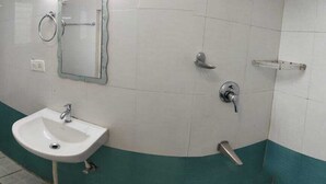 A bathroom with a toilet, sink, and shower. - Hotel Fiesta Grand (Bengaluru)
