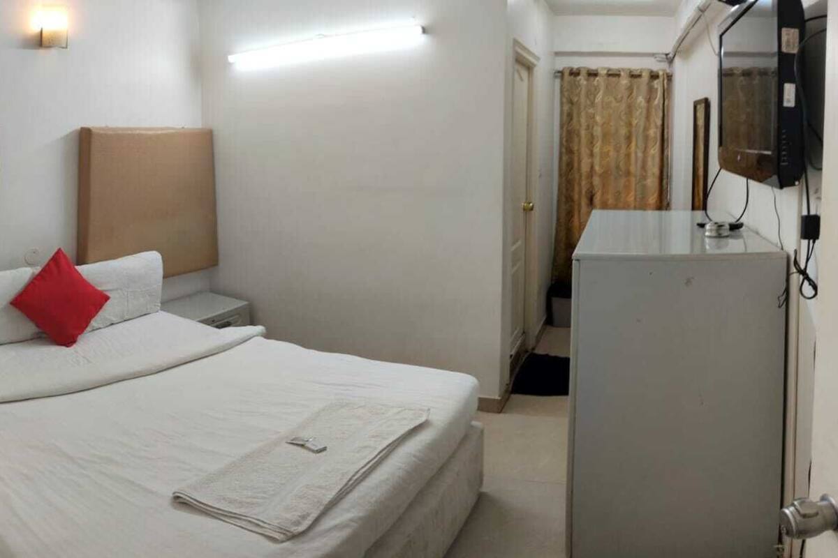 A hotel room with a bed, a nightstand, a television, and a desk.