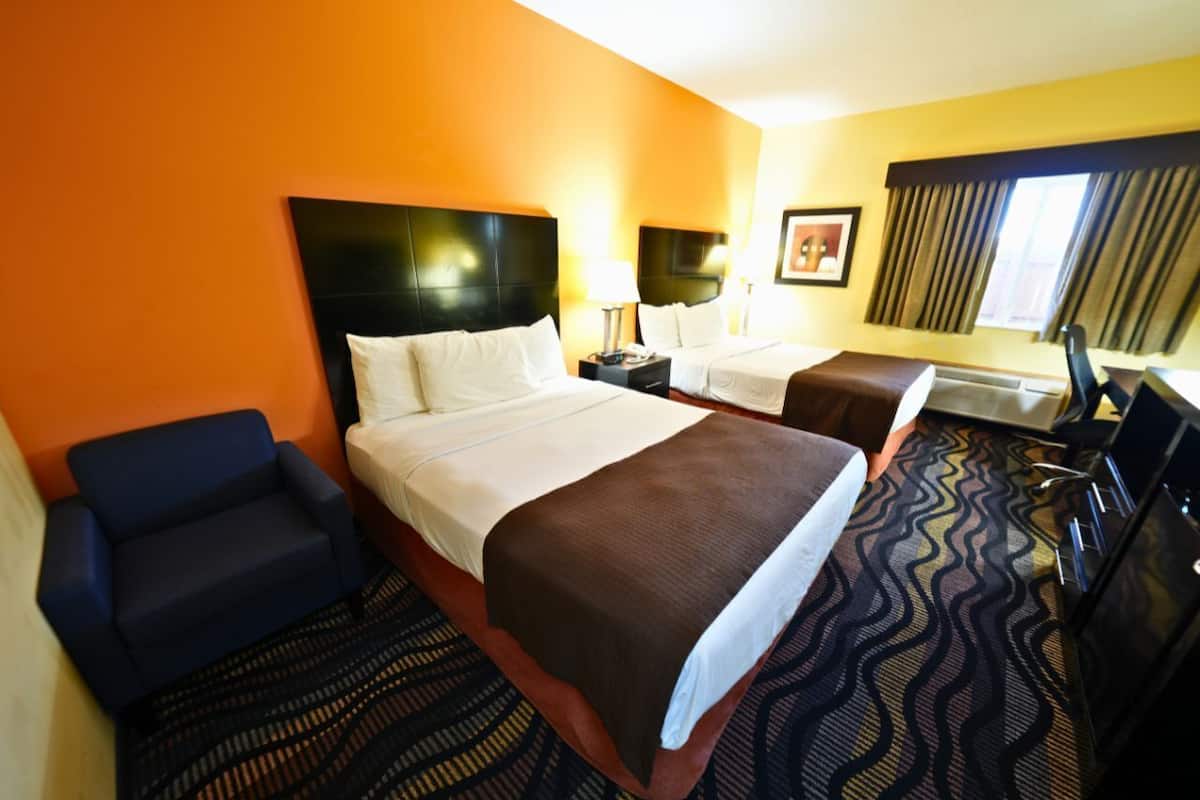 Een hotelkamer met twee bedden, een slaapbank, een bureau en een televisie.