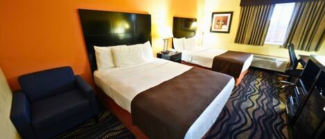A hotel room with two beds, a sofa, a desk, and a TV.