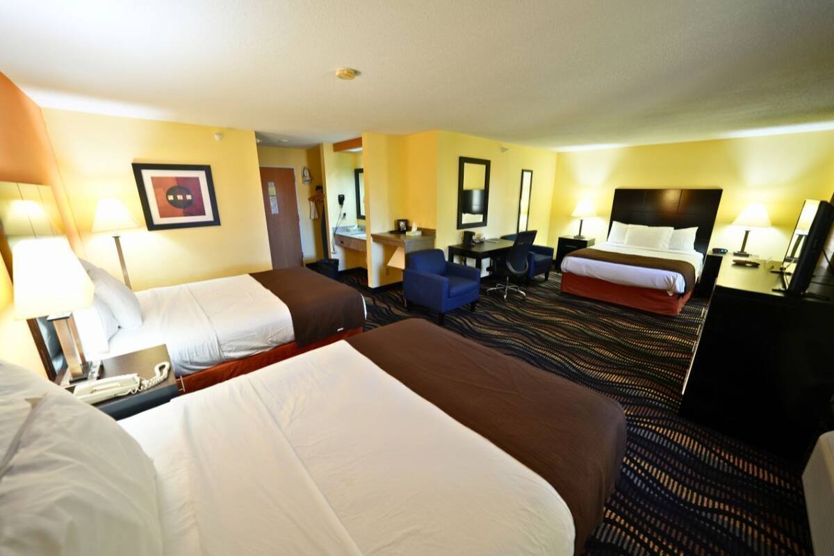 Een hotelkamer met twee bedden, een bureau, een stoel en een televisie.