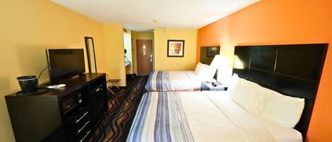 A hotel room with two beds, a desk with a TV, and a dresser.