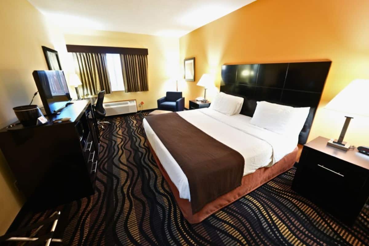 Een hotelkamer met een bed, een bureau, een stoel, een televisie en een raam met gordijnen.