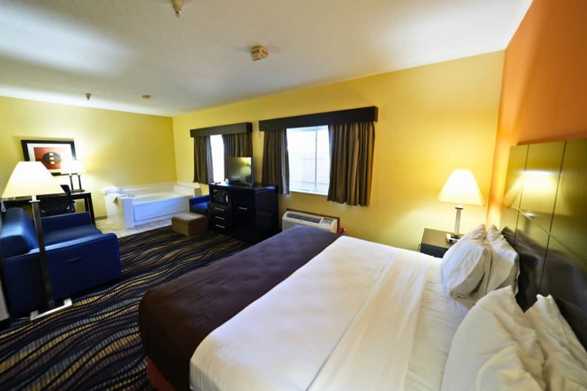 Een hotelkamer met een groot bed, een bureau, een stoel, een bank en een bad.