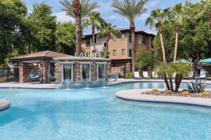 A pool area with a water feature, lounge chairs, and palm trees. - The Laurel Apartments in Chandler (Chandler)