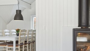 A dining area with a white table and chairs, a hanging pendant light, and a wood-burning stove. - "Janik" - 1.3km from the sea by Interhome (Græsted)
