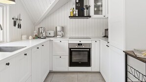 A compact kitchen with white cabinetry, a built-in oven, a coffee maker, and a hanging light fixture. - "Janik" - 1.3km from the sea by Interhome (Græsted)