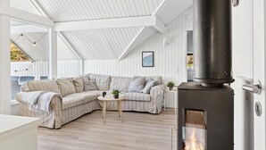A cozy living room with a sectional sofa, a small round table, and a wood-burning stove. - "Janik" - 1.3km from the sea by Interhome (Græsted)