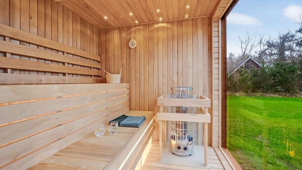 Un sauna en bois avec des bancs, un chauffage et une horloge au mur.