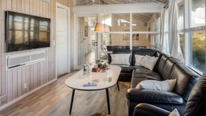 Ein modernes Wohnzimmer mit einem großen Fernseher, einer Couch und einem Couchtisch.
