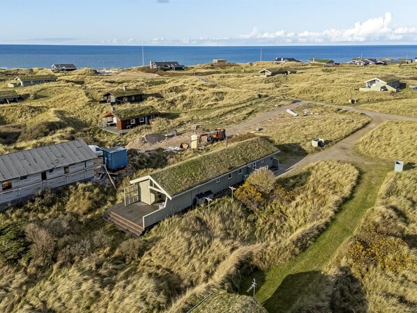 A coastal area with houses, a large building, and a tractor.